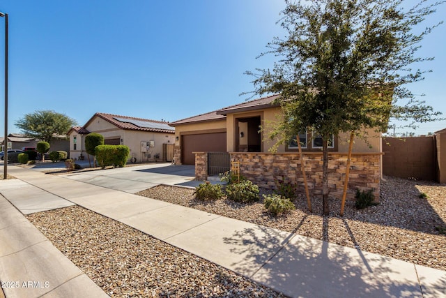 view of front of house with an attached garage, fence, stone siding, driveway, and stucco siding