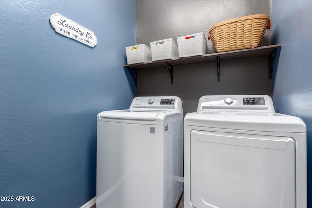 clothes washing area with a textured wall, laundry area, and washing machine and dryer