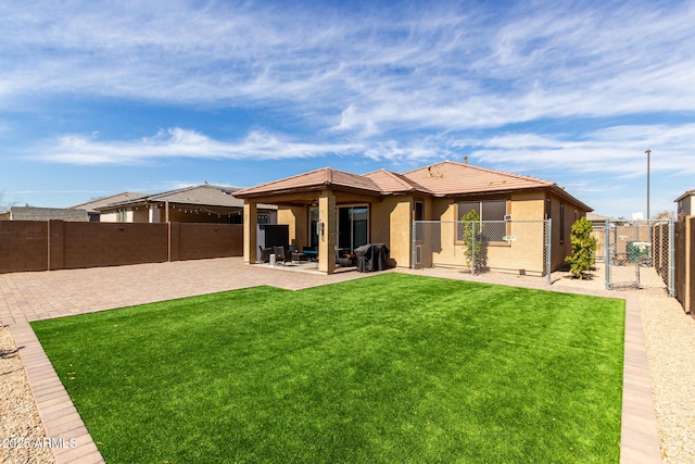 back of property featuring a fenced backyard, a yard, a gate, stucco siding, and a patio area