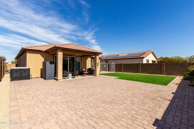 rear view of house featuring a tiled roof, a patio area, a fenced backyard, and stucco siding