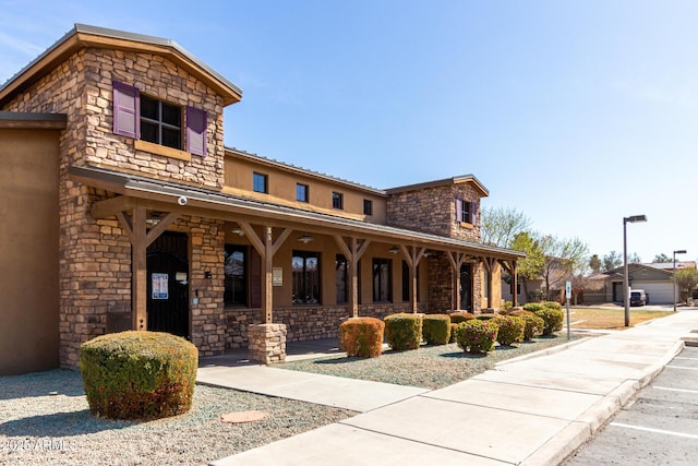 view of front facade featuring a porch, stone siding, and stucco siding