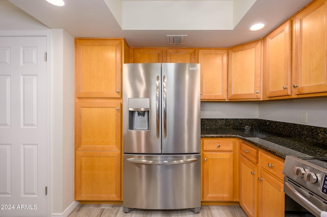 kitchen featuring dark stone counters, stainless steel appliances, and light hardwood / wood-style floors