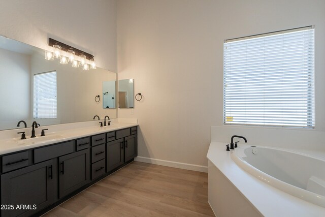 14771 W Columbus Ave, Goodyear, AZ 85395 - bathroom featuring wood finished floors, a garden tub, double vanity, and baseboards