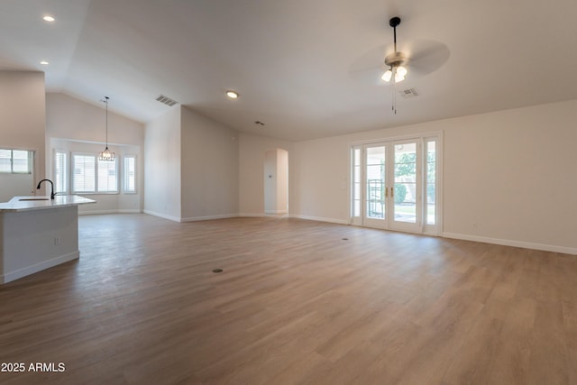14771 W Columbus Ave, Goodyear, AZ 85395 - unfurnished living room featuring ceiling fan, a sink, light wood-type flooring, arched walkways, and lofted ceiling