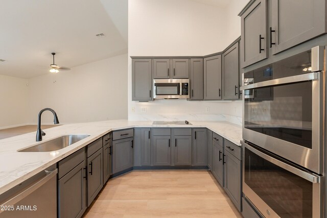 14771 W Columbus Ave, Goodyear, AZ 85395 - kitchen featuring stainless steel appliances, a sink, gray cabinetry, light wood-style floors, and light stone countertops