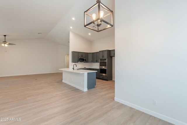 14771 W Columbus Ave, Goodyear, AZ 85395 - kitchen featuring stainless steel appliances, open floor plan, a sink, lofted ceiling, and light wood finished floors