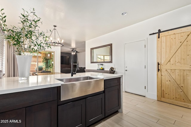25218 W Carson Ct, Buckeye, AZ 85326 - kitchen with light countertops, a sink, light wood-style floors, a chandelier, and hanging light fixtures
