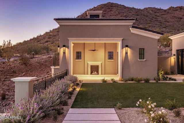 exterior entry at dusk featuring a mountain view and a lawn