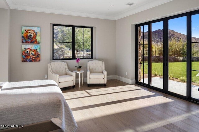 bedroom with ornamental molding, a mountain view, wood-type flooring, and multiple windows