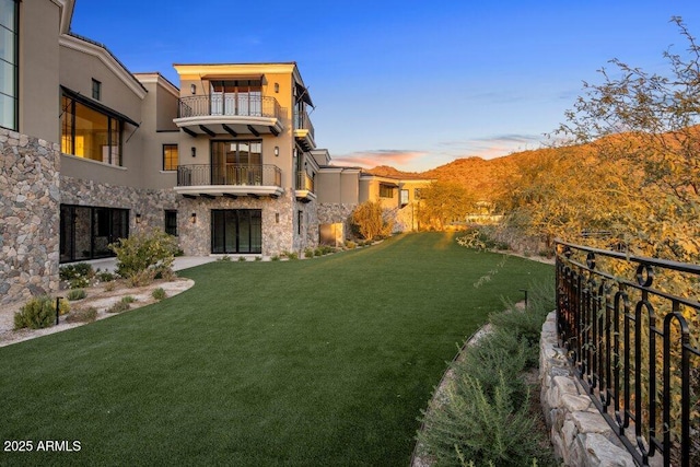 yard at dusk featuring a balcony