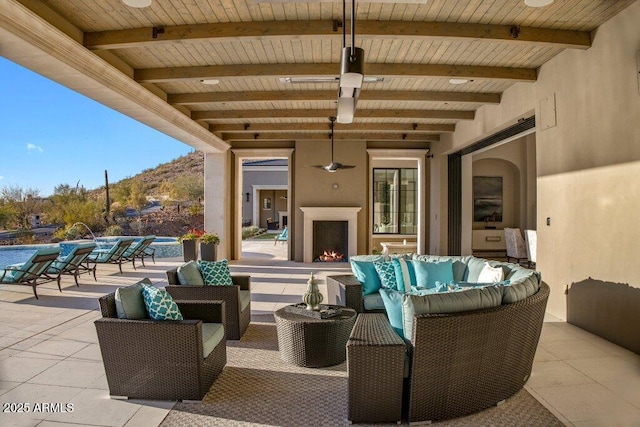 view of patio / terrace with ceiling fan, an outdoor living space with a fireplace, and a mountain view