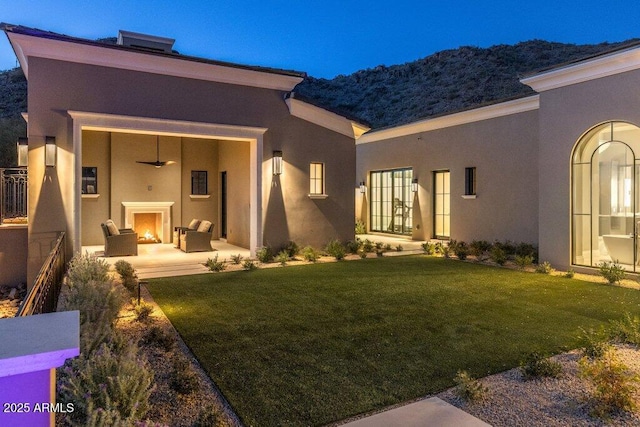 back of property featuring an outdoor fireplace, a yard, and a patio