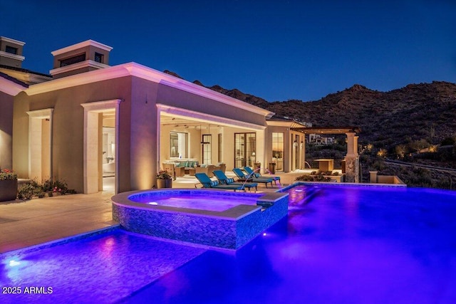 pool at twilight with an in ground hot tub and a patio