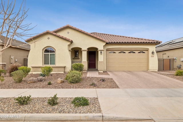 mediterranean / spanish home with a garage, decorative driveway, a tiled roof, and stucco siding