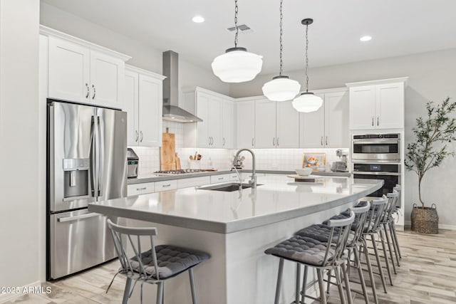 kitchen with decorative backsplash, appliances with stainless steel finishes, a breakfast bar, wall chimney range hood, and a sink