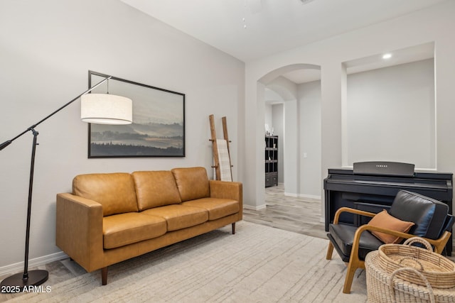 living room featuring light wood-style floors, baseboards, and arched walkways