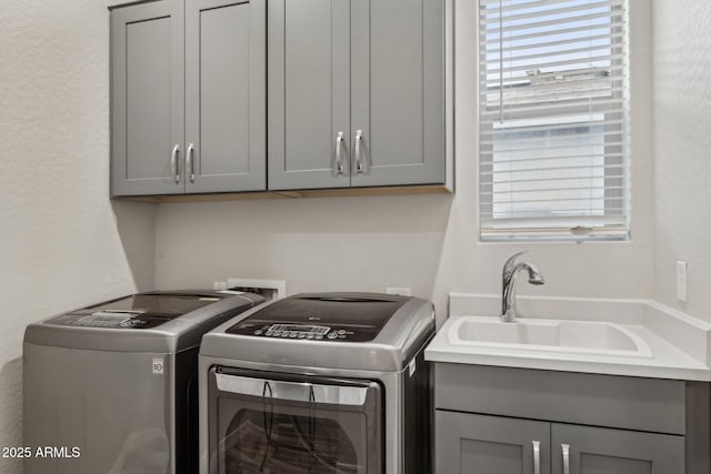 washroom with washing machine and clothes dryer, a sink, and cabinet space