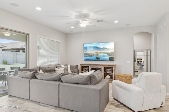 living area featuring light wood-type flooring, visible vents, arched walkways, and recessed lighting