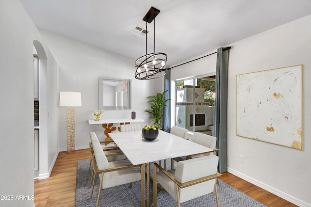 811 S Pearl Dr, Gilbert, AZ 85233 - dining room featuring light wood finished floors, arched walkways, baseboards, visible vents, and a notable chandelier