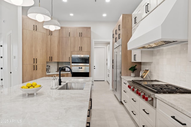 kitchen with premium range hood, pendant lighting, backsplash, appliances with stainless steel finishes, and light brown cabinets