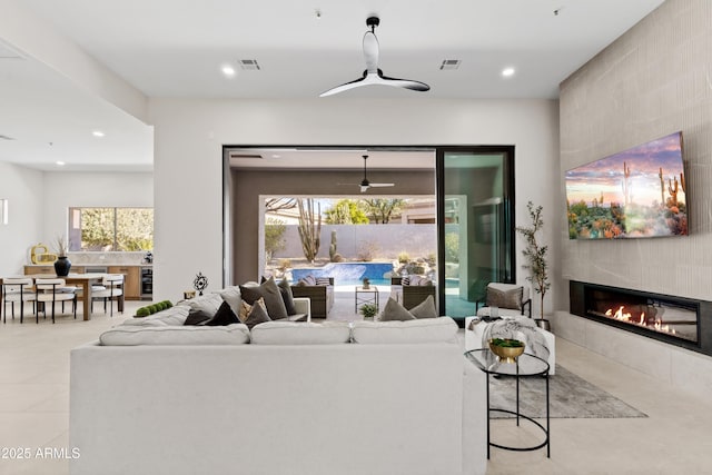 living room featuring a tile fireplace and ceiling fan