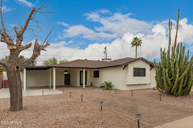 ranch-style home with a carport, driveway, and a shingled roof