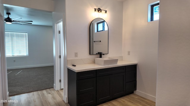 bathroom with ceiling fan, baseboards, wood finished floors, and vanity