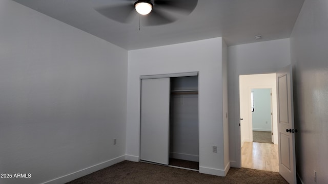 unfurnished bedroom with dark colored carpet, baseboards, a closet, and ceiling fan