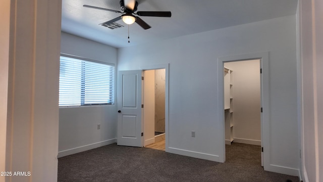 unfurnished bedroom featuring a walk in closet, carpet floors, and baseboards