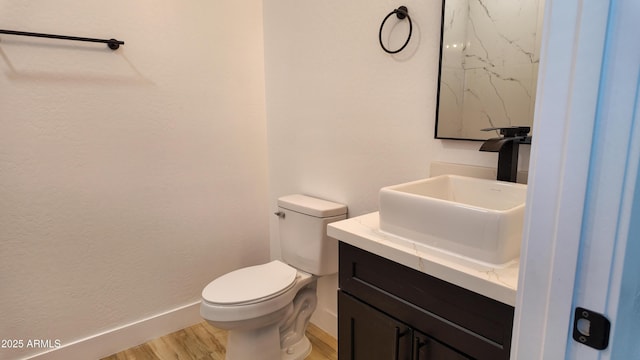 bathroom with wood finished floors, baseboards, toilet, and vanity