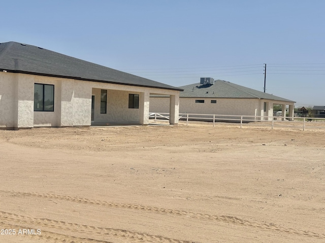 rear view of property featuring stucco siding and fence