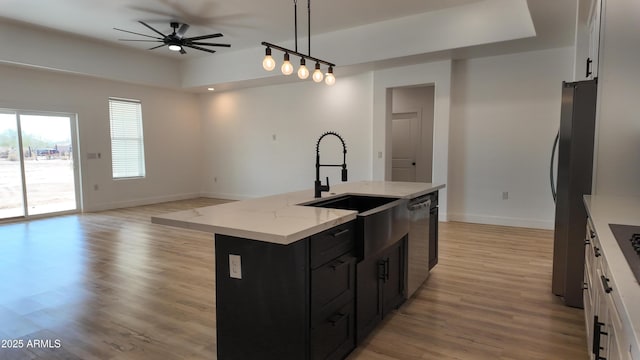 kitchen with dark cabinetry, appliances with stainless steel finishes, baseboards, ceiling fan, and a sink