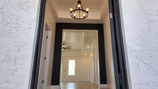 doorway to outside with a raised ceiling, a chandelier, and a ceiling fan