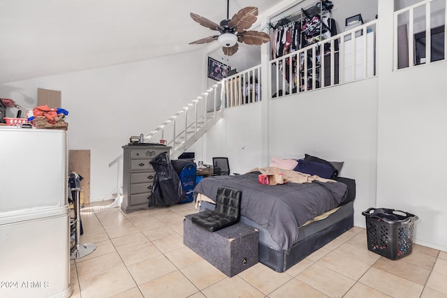 bedroom with high vaulted ceiling, ceiling fan, white refrigerator, and light tile patterned flooring