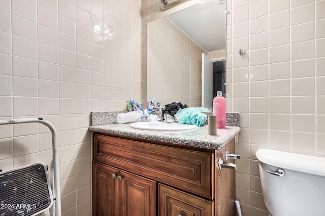 bathroom featuring tile walls, vanity, and toilet