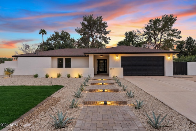 ranch-style home with driveway, a garage, fence, a front lawn, and stucco siding