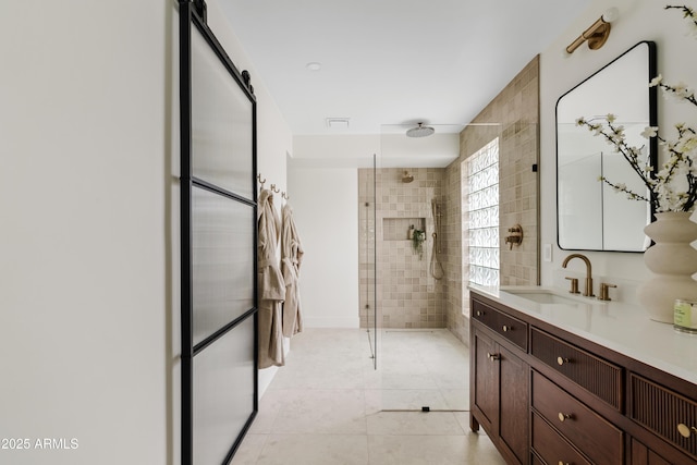 bathroom with tile walls, tiled shower, vanity, and tile patterned floors