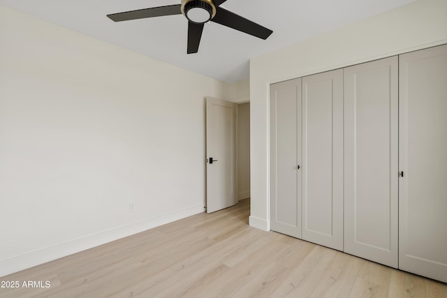 unfurnished bedroom featuring ceiling fan, light wood finished floors, a closet, and baseboards