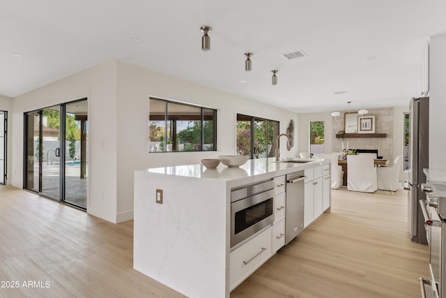 kitchen featuring appliances with stainless steel finishes, plenty of natural light, a sink, and white cabinets