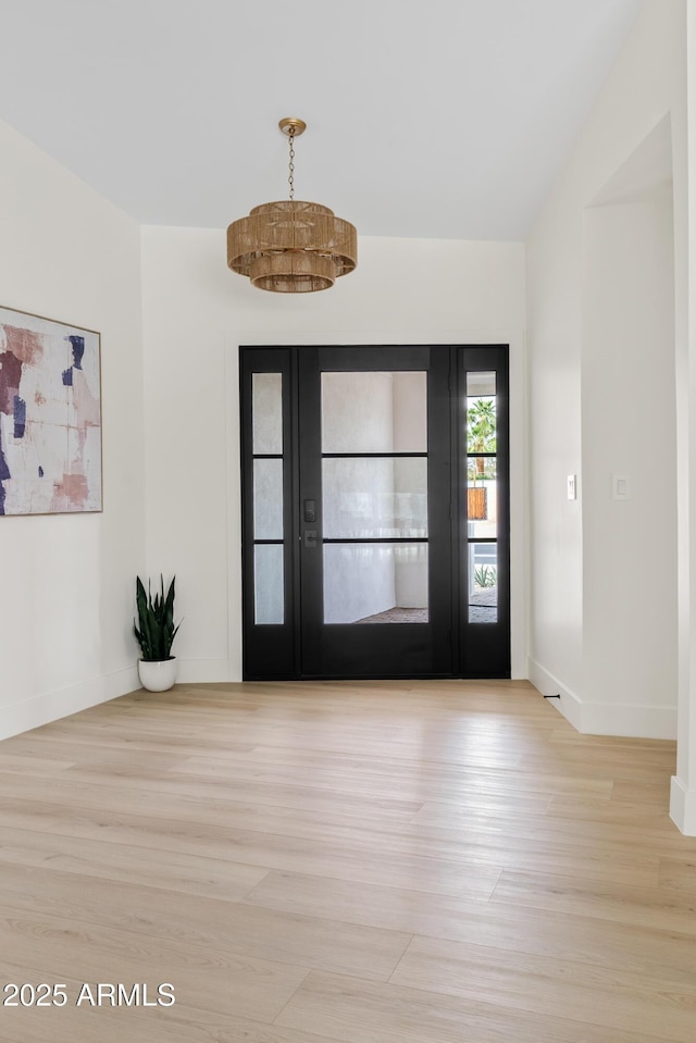 foyer entrance with lofted ceiling, wood finished floors, and baseboards