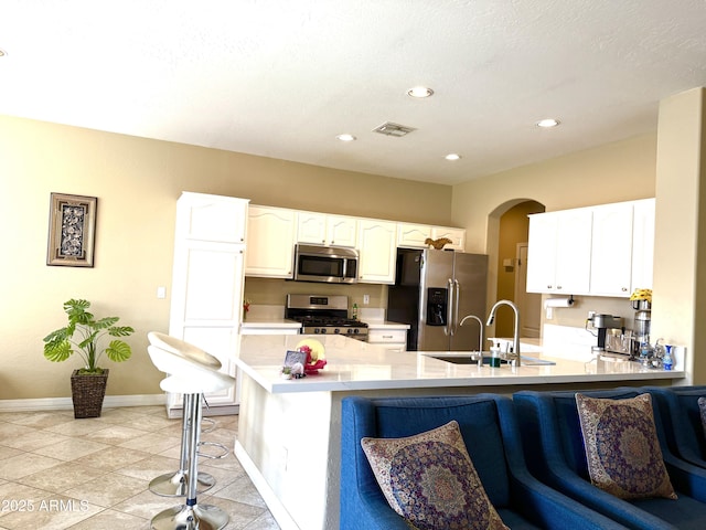 kitchen featuring sink, white cabinets, a kitchen breakfast bar, kitchen peninsula, and stainless steel appliances