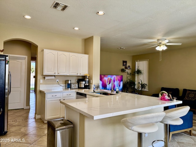 kitchen featuring white cabinetry, a kitchen bar, stainless steel appliances, and kitchen peninsula