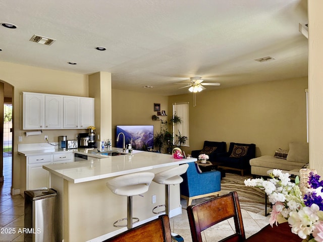 kitchen featuring sink, ceiling fan, white cabinetry, a kitchen breakfast bar, and kitchen peninsula