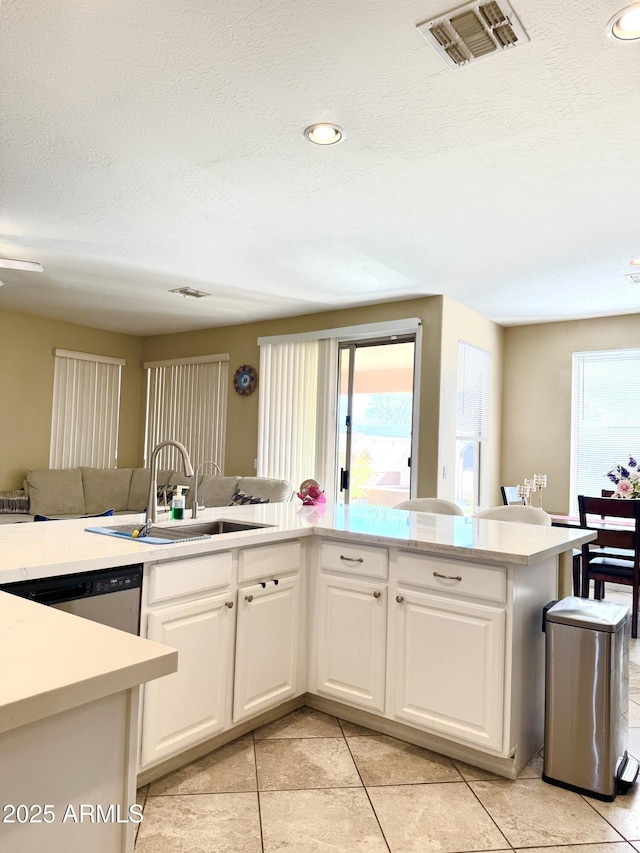 kitchen featuring sink, stainless steel dishwasher, white cabinets, and kitchen peninsula