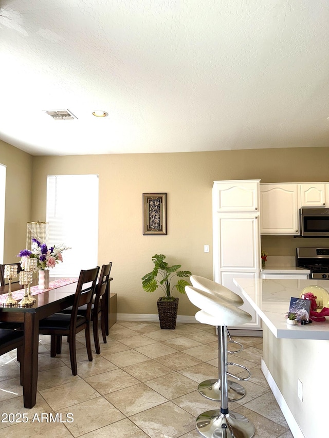 tiled dining space featuring a textured ceiling