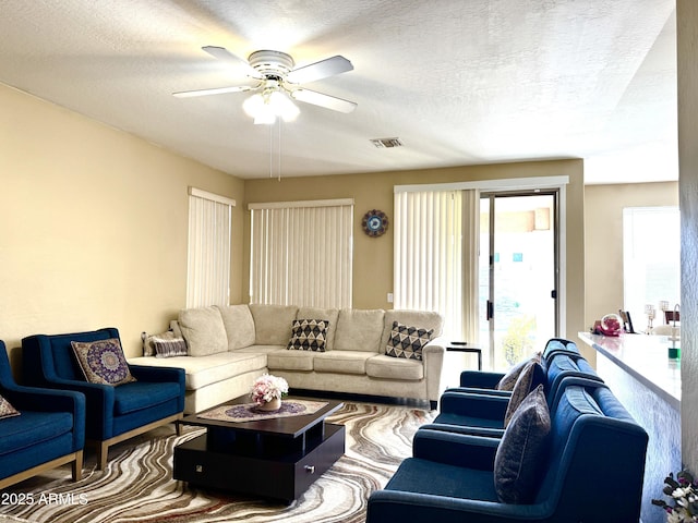 living room with ceiling fan and a textured ceiling