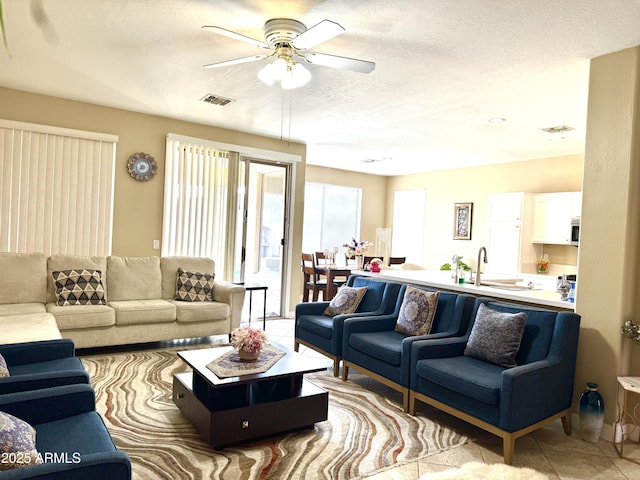 tiled living room featuring sink, a textured ceiling, and ceiling fan