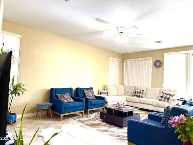 living room featuring light tile patterned flooring, a textured ceiling, and ceiling fan