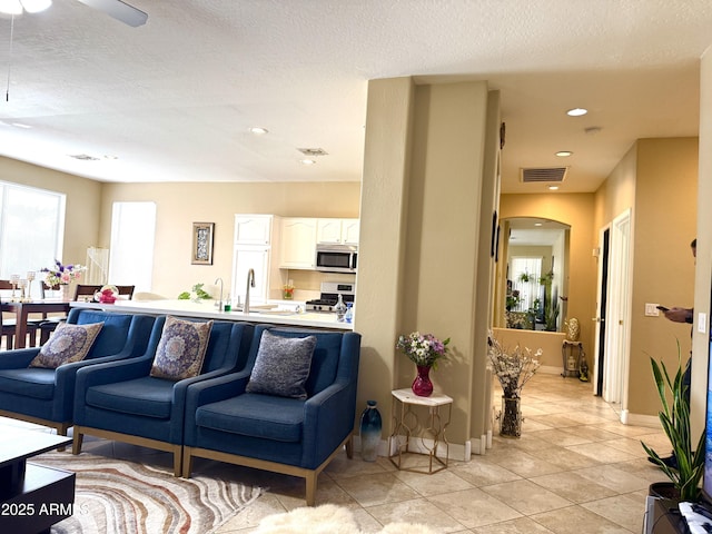 living room featuring light tile patterned flooring, sink, and a textured ceiling