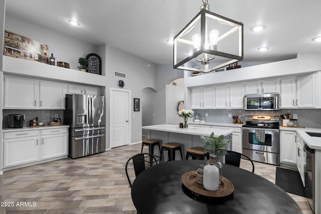 2111 E Rawhide St, Gilbert, AZ 85296 - kitchen featuring appliances with stainless steel finishes, arched walkways, tasteful backsplash, light countertops, and white cabinets